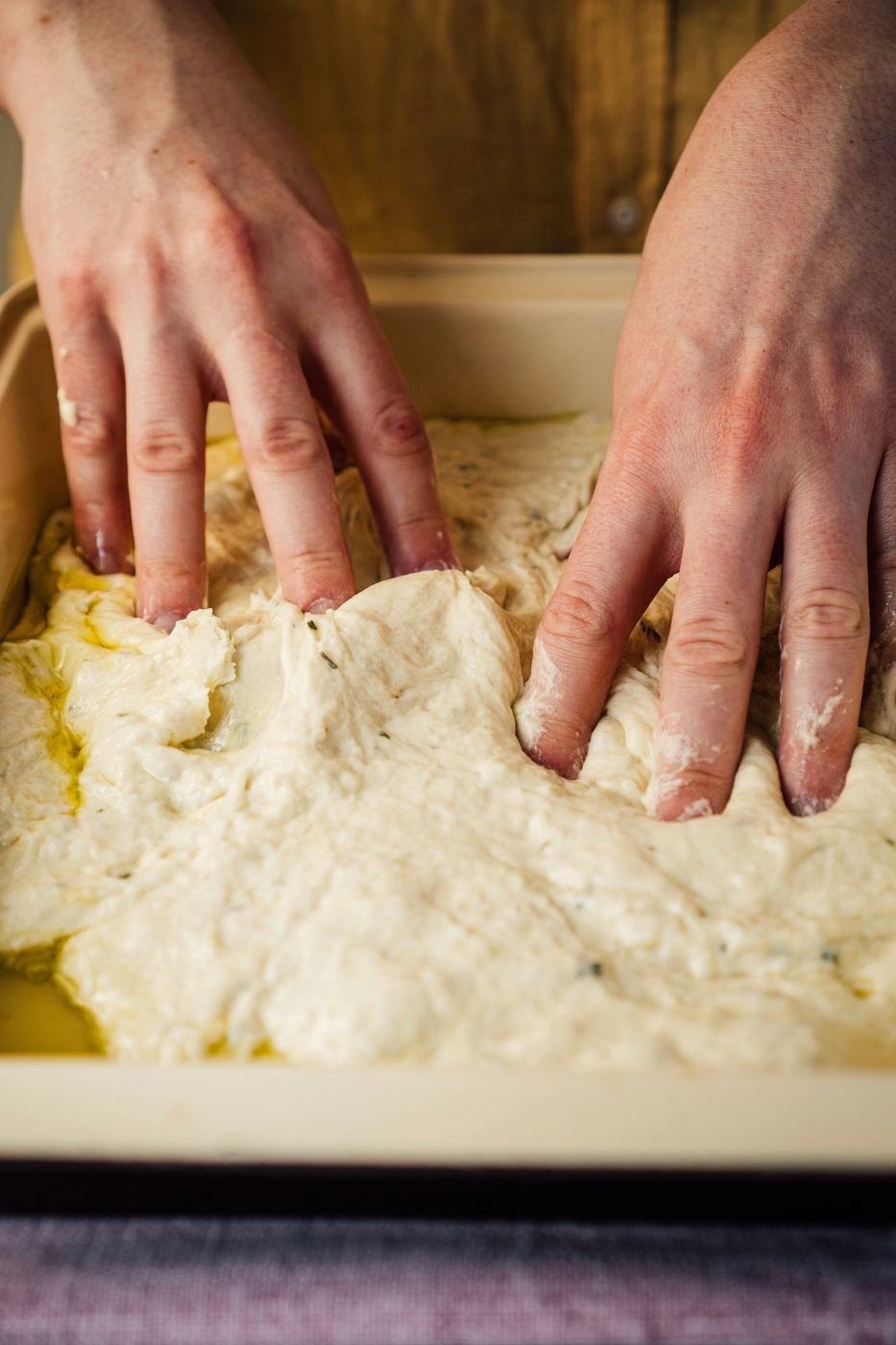 Mani al lavoro nella preparazione della focaccia